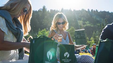 Two women enjoying gourmet picnic bags at a Deer Valley summer concert.