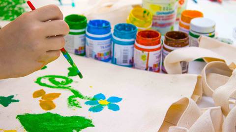 Child painting a canvas tote bag.