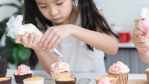 Young girl decorating cupcakes.