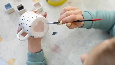 Girl painting a ceramic mug