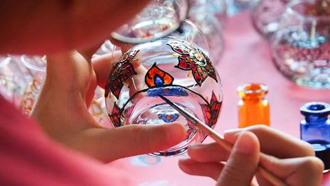 Girl painting designs on glass vase