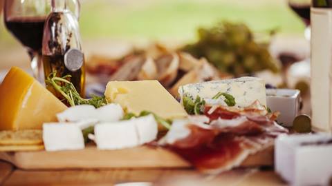 Cheese and charcuterie board with wine glass.