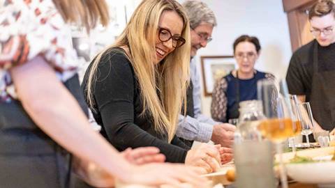 Woman making pasta and smiling in a Deer Valley Creative Academy class.