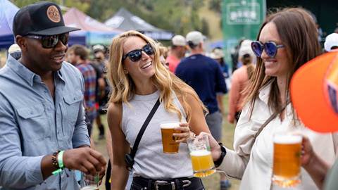 Man and two women holding beer and laughing at Deer Valley Mountain Beer Festival in Park City, Utah.