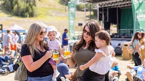 Two moms holding babies and beer at Deer Valley Mountain Beer Festival in Park City, Utah.