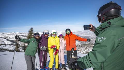 Deer Valley Mountain Host taking group photo of skiers during Mountain Host Tour.
