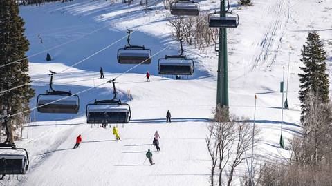Deer Valley Mountain Host Tour skiing together under chairlift.