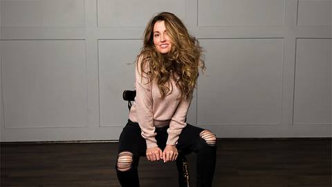 Musician Saranade smiling directly at camera while sitting on a chair.