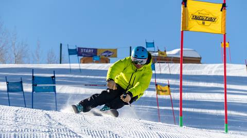 Guest wearing yellow jacket is skiing down the race hill at Deer Valley Resort.