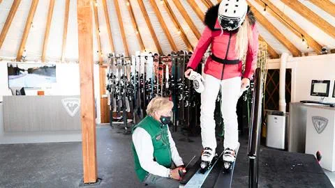 Deer Valley rental tech assisting guest in putting on Rossignol high performance skis.