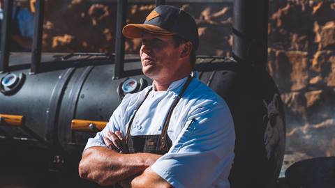 Chef Ryan Arensdorf standing in front of smoker