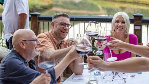 Guests drinking red wine on the deck at Deer Valley Café in the summer at a Taste of Luxury event.