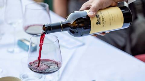 Server pouring red wine into a glass from a Duckhorn bottle.