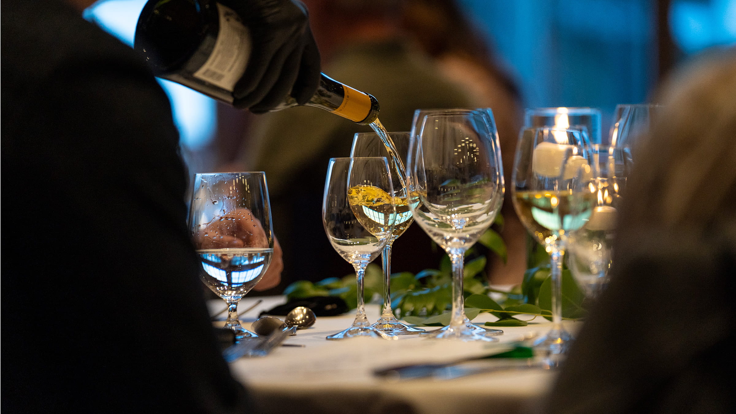 A server is pouring wine into glasses.