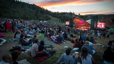 Deer Valley summer concert at sunset. The amphitheater is beautifully lit with orange and pink lights in the background.