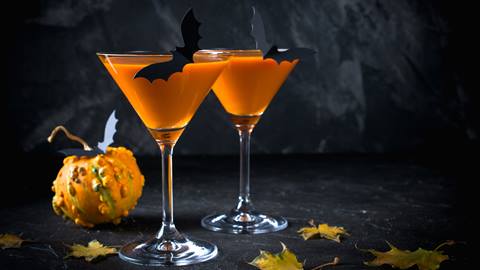 Halloween-themed cocktail with spiders and pumpkin decorations.