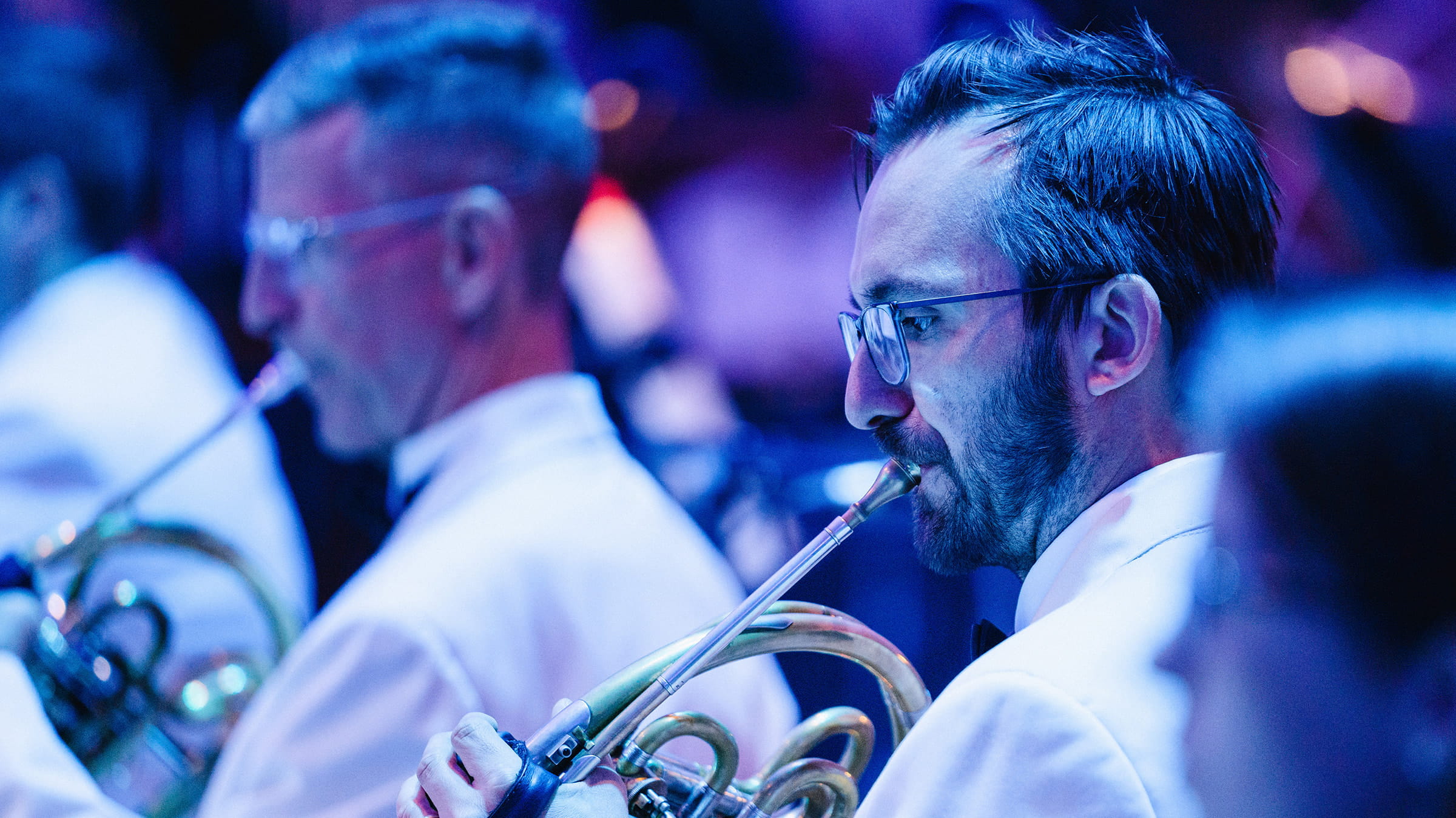 Two men playing French horns in concert