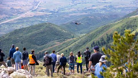 Deer Valley guests watching a helicopter fly chairlift towers into Deer Valley's new terrain during Expanded Excellence: Future in Flight event.