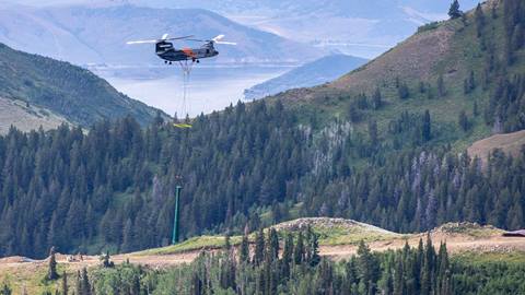 Helicopter flying chairlift towers into Deer Valley's new terrain during Expanded Excellence: Future in Flight event.