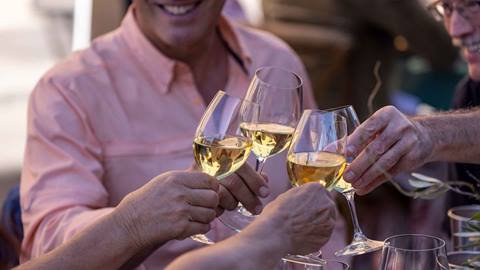 People doing a cheers with white wine outside on Main Street in Park City for the annual Savor the Summit event.