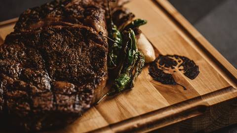 Grilled steak displayed on wooden cutting board.