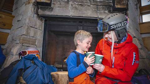 Mother and son with hot chocolate inside Cushing's Cabin at Deer Valley.
