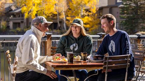 A father eating lunch on the deck of Deer Valley Café with his adult children.