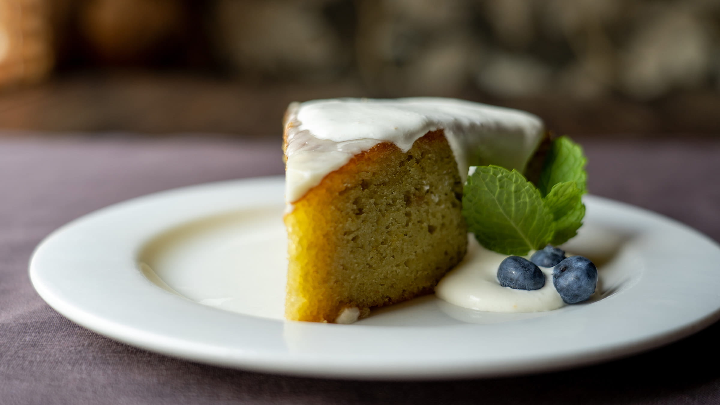 Cake served on a white plate with blueberries and sweet cream.