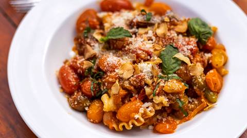 Warm pasta served with sauted tomatoes and basil, topped with cheese.
