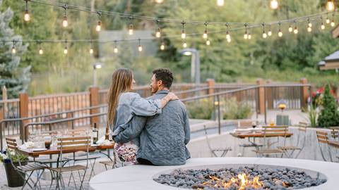 Couple sitting by the fire on the outdoor patio at The Brass Tag in the summer.