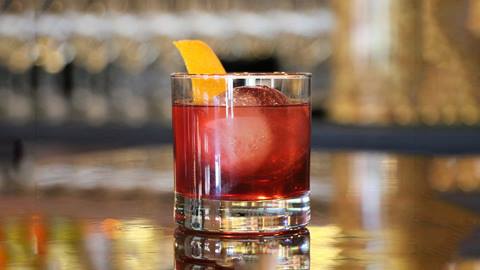 Cocktail with orange peel displayed on counter.