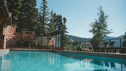 Couple looking at the mountain view from the pool at Stag Lodge in the summer.