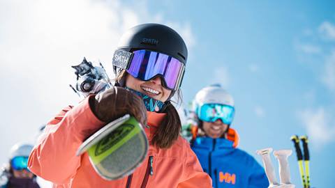 Woman walking with man and carry Rossignol skis.