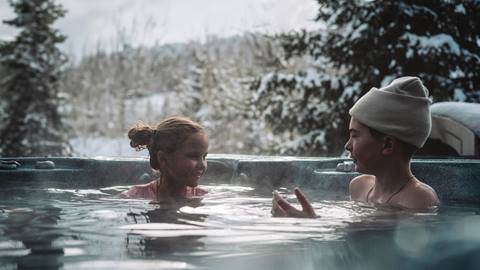 two children enjoy a warm outdoor hot tub surrounded by snowy trees and mountain views at deer valley resort