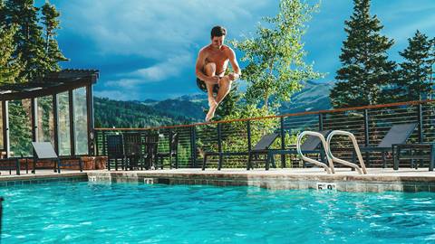 Man diving into a pool during a sunny summer day at Deer Valley Resort.