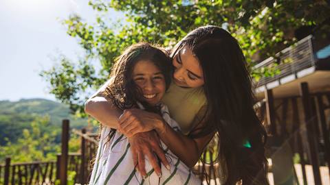 Mother and daughter hugging outside in the summer.