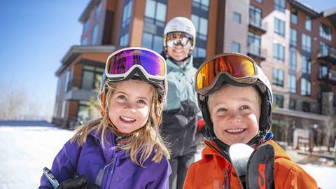 Deer Valley lodging guests standing outside ski-in/ski-out lodging property with ski gear.