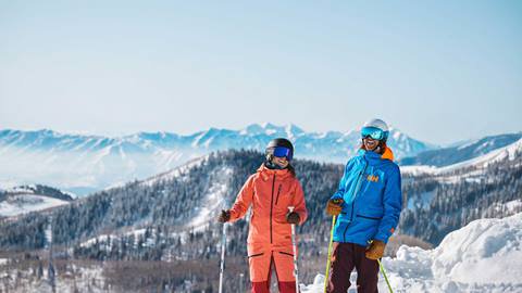 Two skiers standing on mountain laughing at Deer Valley.