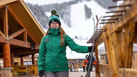 Female guest services attendance carrying guest skis. 