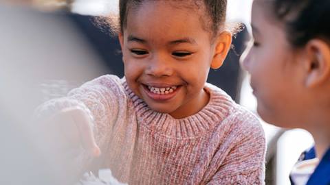 Young girl eating snack with friend
