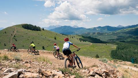 Family of four mountain biking at Deer Valley on a bright summer day.