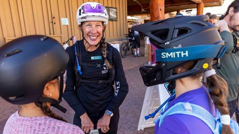 Two mountain bikers talking to smiling Deer Valley Bike Instructor