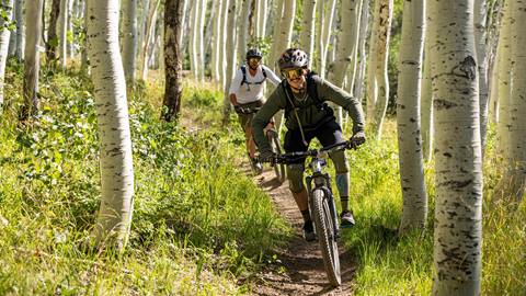 Deer Valley Mountain Bike Instructor biking with student through aspen trees.