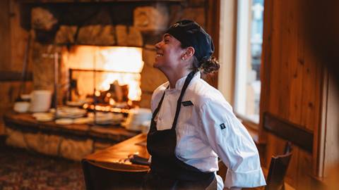 Deer Valley food and beverage staff member leaning against chair by fireplace