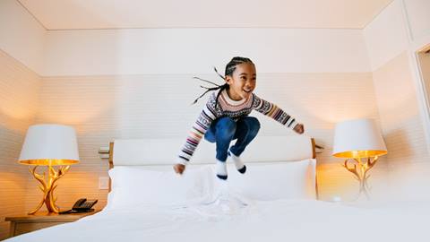 happy child jumping on bed at deer valley resort