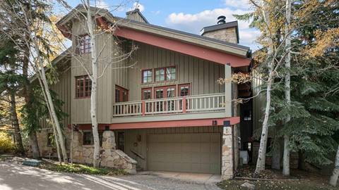 exterior view of the cache at silver lake vacation rental at deer valley resort, showing a multi-level mountain townhome surrounded by trees in park city, utah.