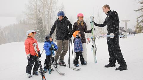 Family of five being helped by Stein Eriksen Guest Service attendant on the slopes
