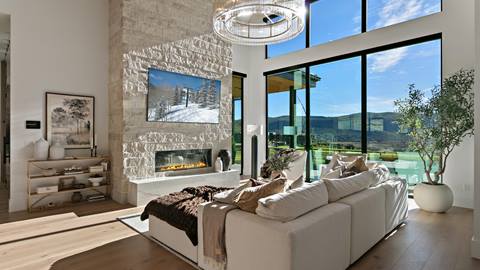 Living room with fireplace and floor-to-ceiling windows inside Deer Valley's luxury lodging property, SkyRidge 1643.