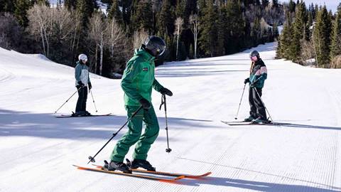 Deer Valley Ski Instructor standing on-mountain with two teenage students in Park City, Utah.