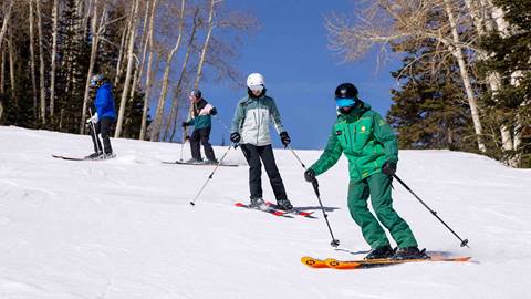 Deer Valley Ski Instructor skiing with three students in Park City, Utah.